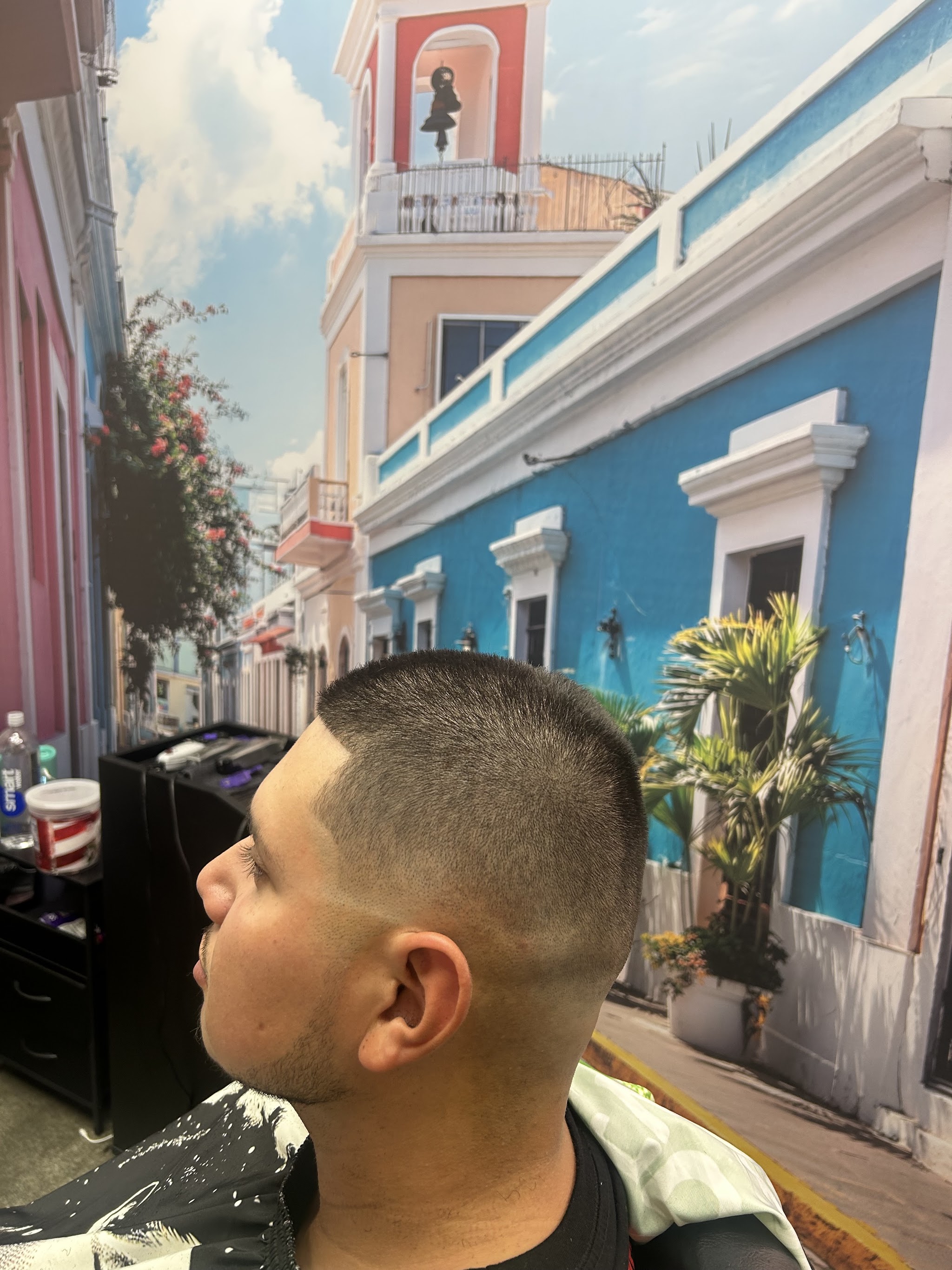 A client mid-cut in front of the Old San Juan street mural on the shop wall